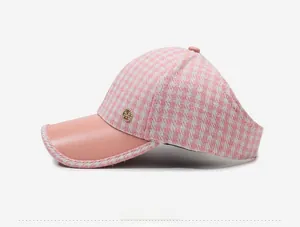 Détail de la visière pied-de-poule rose avec bord en cuir et breloque en métal doré