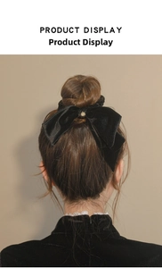 Detail of elegant black velvet bow hair scrunchie with golden charm on hair bun