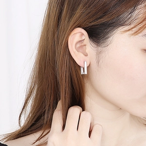 Minimalist silver rectangular stainless steel earrings shown on female model ear