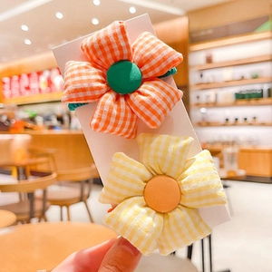 Close-up of floral fabric hair ties in orange and yellow gingham for young girls