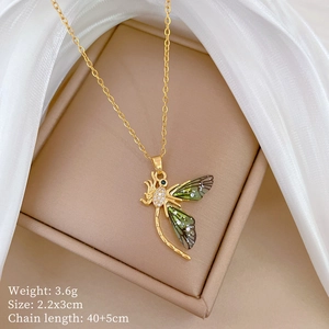Macro detail of gold dragonfly pendant with green wings and pavé diamonds on silk