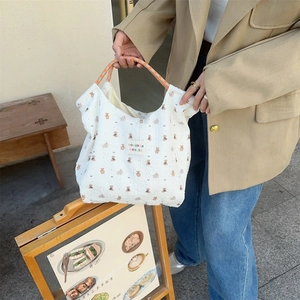 Detail of white waffle texture handbag with cartoon bear prints and woven handles