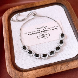 Detail of silver slide bracelet with seven oval black stones in halo setting