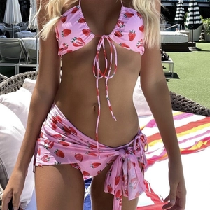 Three-piece pink bikini set with strawberry print and mesh sarong by the pool