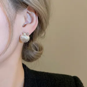 Matte silver apple stud earrings with star engraving on elegant female model