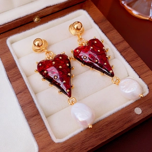Detail of vintage heart earrings with red enamel and pearl in a velvet jewelry box