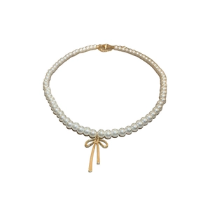 French vintage faux pearl choker necklace with a gold bow pendant on white background