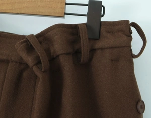 Détail de la jupe en laine marron foncé montrant les passants et le bouton
