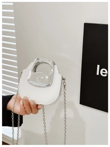 Detail of white mini chain bag with silver metallic handle and polished semi-circle design