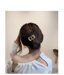 Golden metal chain link hair claw clip shown on a woman's elegant hairstyle