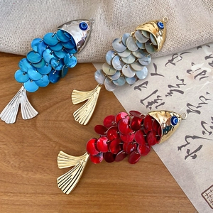 Detail of fish-shaped hair clips with evil eye beads and scales on rustic background