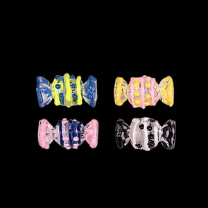 Close-up of four colorful candy-shaped glass beads for DIY jewelry making
