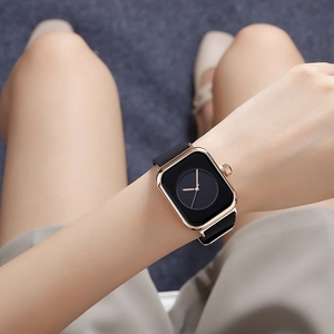 Wrist shot of stylish square rose gold watch with black silicone strap on a female wrist