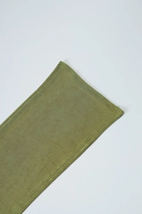 Detailed close-up of green ribbed fabric showing fine vertical texture and hem stitching