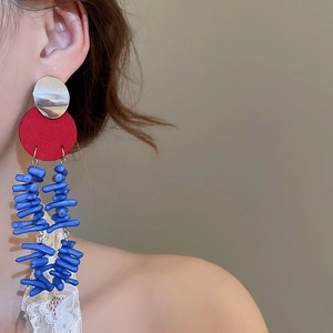 Détail de boucles d'oreilles pendantes rouges et bleues avec texture métal et résine