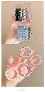 Dettaglio di elastici per capelli a spirale colorati in scatola e tenuti in mano