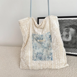 Detail of canvas tote bag featuring blue lace pocket and stylish brand label on white texture