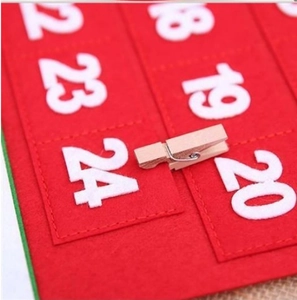 Red felt Christmas advent calendar hanging with numbered pockets and small wooden clips