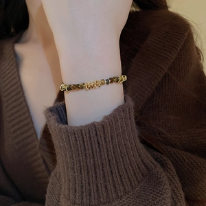 Close-up of golden metal beads and tiger eye stone bracelet worn on a woman's wrist