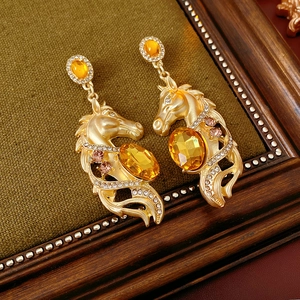 Makroaufnahme von Vintage-Pferdekopf-Ohrringen mit orangefarbenen Steinen und Strass