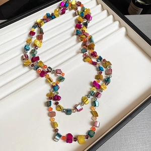 Detailed view of colorful floral ceramic bead necklace on a white jewelry display tray
