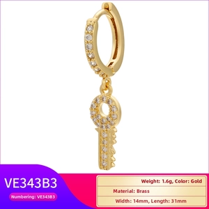 Detailed macro view of gold brass key pendant earring with zircon micro-pave crystals