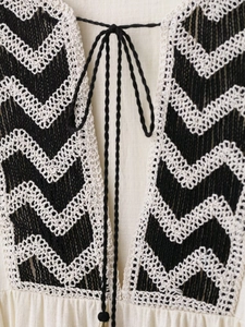 Close-up of bohemian neckline with crochet wave lace and black tie drawstring detail