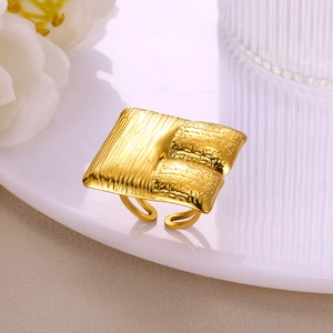 Detail of gold square ring featuring dual-texture vertical stripes and hammered patterns