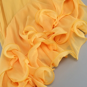 Gros plan sur le tissu mousseline jaune avec volants et coutures détaillés de la robe