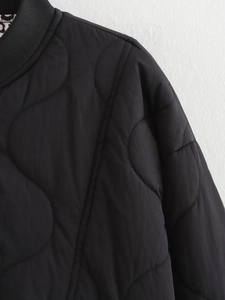 Detailed close-up of black quilted jacket featuring ribbed collar and stitching texture
