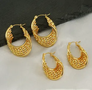 Detail of gold braided twist earrings with a textured weave pattern and hoop clasp