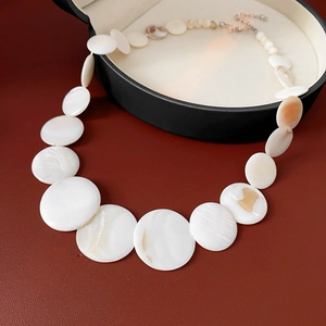 Detail of natural shell necklace with white circular pearls in a black round jewelry box