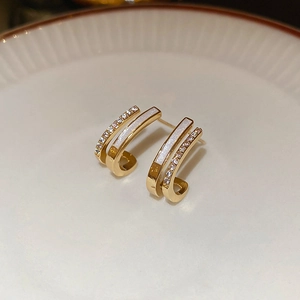 Macro shot of gold-plated double-layer J-shaped stud earrings with white enamel inlay