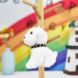 Adorable white plush teddy dog keychain pendant with star collar on a wooden stand