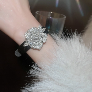 Nahaufnahme eines schwarzen Lederarmbands mit großer silberner Rosenverzierung mit Diamanten