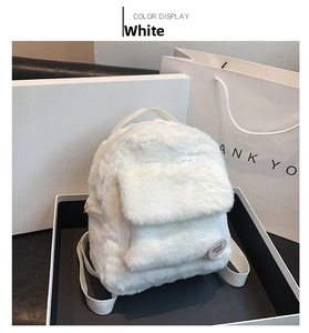 Primer plano detallado de la mini mochila de felpa blanca con etiqueta de buena suerte