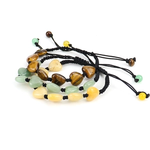 Detailed shot of three woven heart-shaped bracelets with natural tiger eye and aventurine