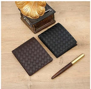 Classic woven leather bifold wallets in black and brown on a professional wooden desk