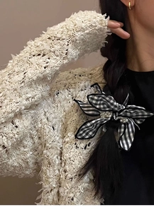Detail of black and white checkered bow hair tie with pearl accents on black braided hair