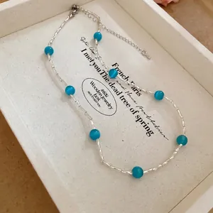 Collana con perle occhio di gatto blu e tubi d'argento su un vassoio bianco