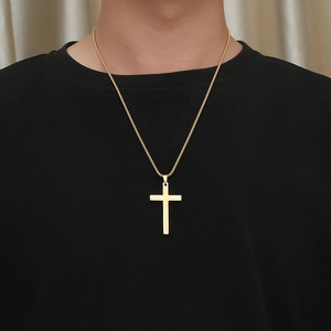 Detail of a gold cross pendant with radiant light texture on a minimalist chain necklace