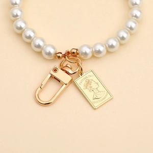 Detailed macro shot of vintage pearl keychain with golden Queen Elizabeth II charm