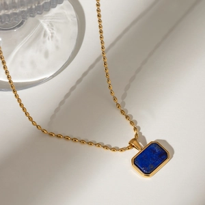 Detailed close-up of 18k gold bead chain with rectangular blue stone pendant