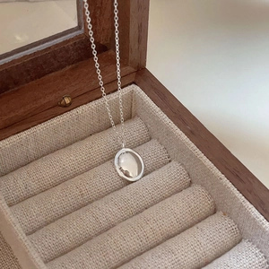 Detail of minimalist 925 sterling silver oval pendant necklace in a wooden jewelry box