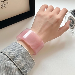 Nahaufnahme eines breiten rosa Acryl-Armreifens in unregelmäßigem Design am Handgelenk