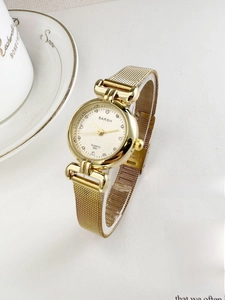 Detailed shot of golden women's quartz watch with milanese mesh band and crystal markers