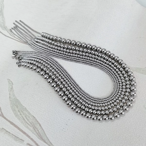 Detailed view of multiple rows of polished stainless steel bead necklaces with metallic luster