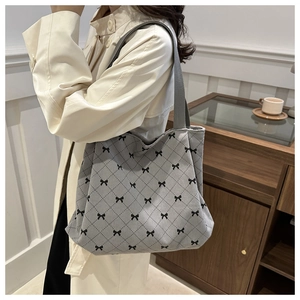 Close-up of a grey tote bag with black bow prints and quilted pattern on a model