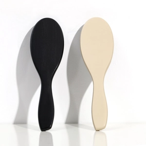 Detail shot of ergonomic black and beige wooden massage hair brushes with long shadows
