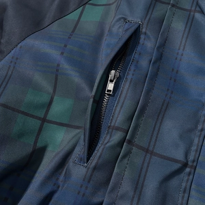 Détail macro de la poche à fermeture éclair sur une veste à carreaux bleu et vert